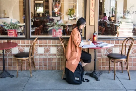 a student works at a cafe outside on schoolwork