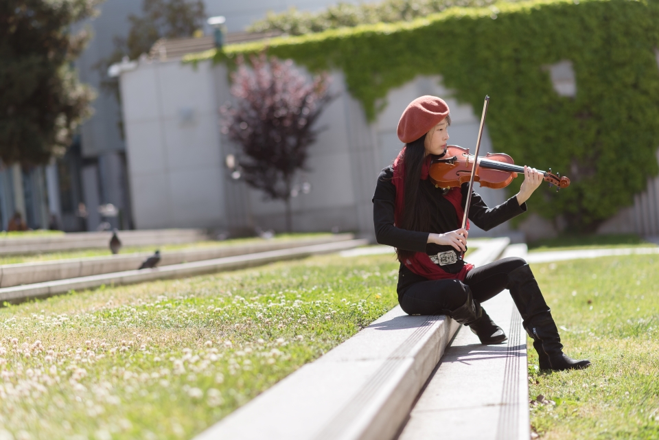 violinist plays sitting on shallow stairs in the grass