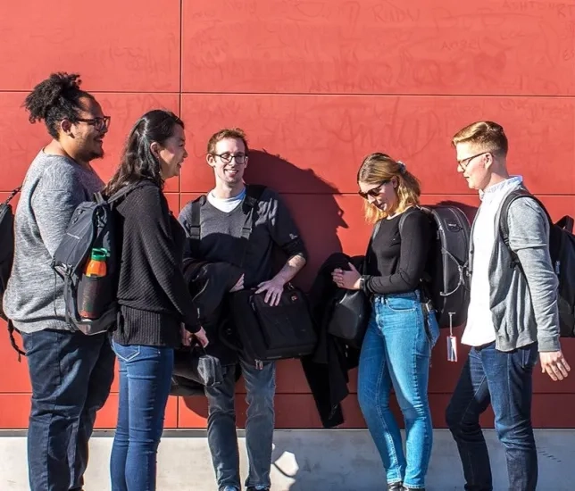 students stand in a group outside talking