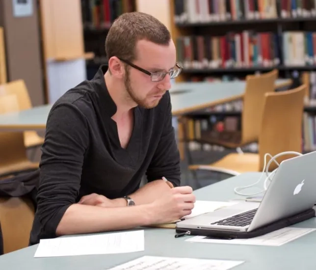 a student sits at their laptop in the library