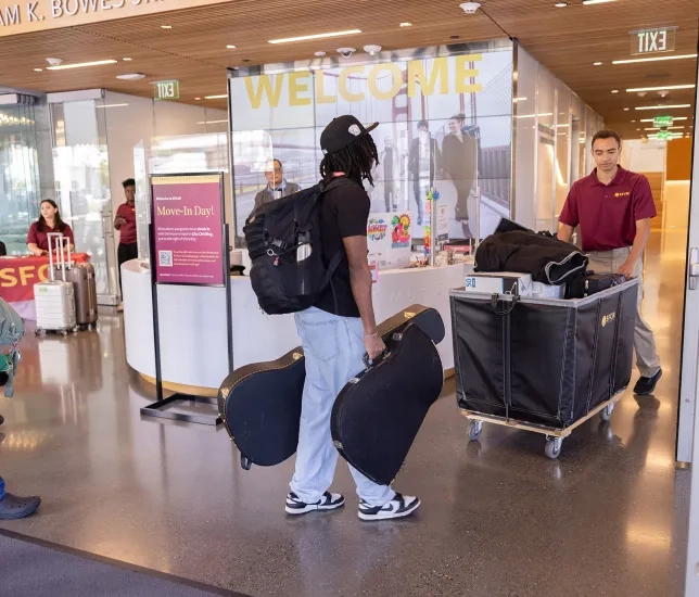 A Resident Advisor helps a student move into the Bowes Center. 