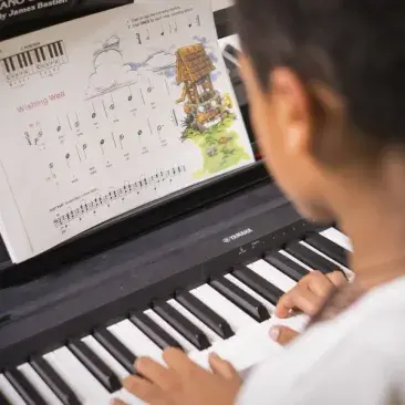 over the shoulder view of a student playing piano