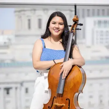 a cellist with her instrument on the rooftop of bowes