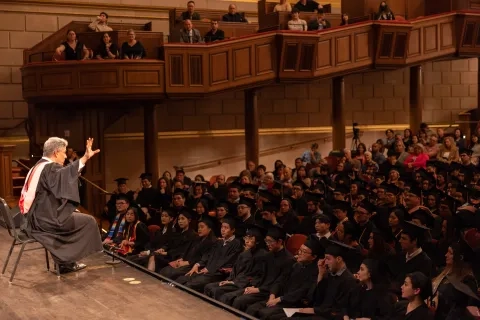 david stull sits in a chair on the edge of the stage addressing the class of 2023