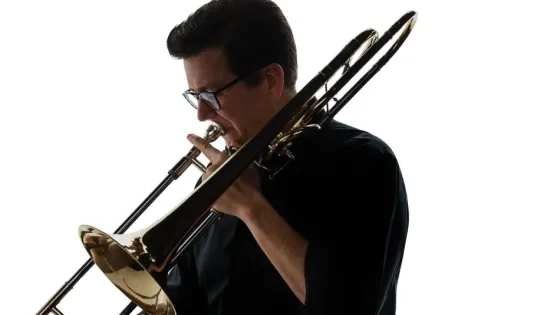 a dramatic shot of tim higgins playing the trombone