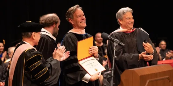 Jake Heggie holds a diploma with dean wright and david stull