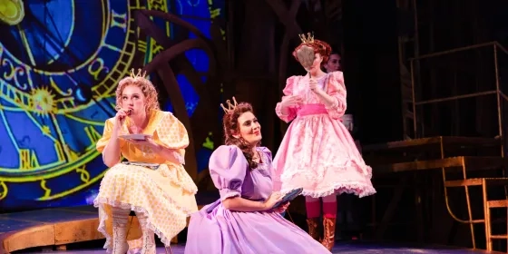 Three singers sing during an opera, they are dressed in gowns