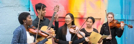 Pre college Photoshoot in Hickory Alley. Students are holding their instruments and smiling