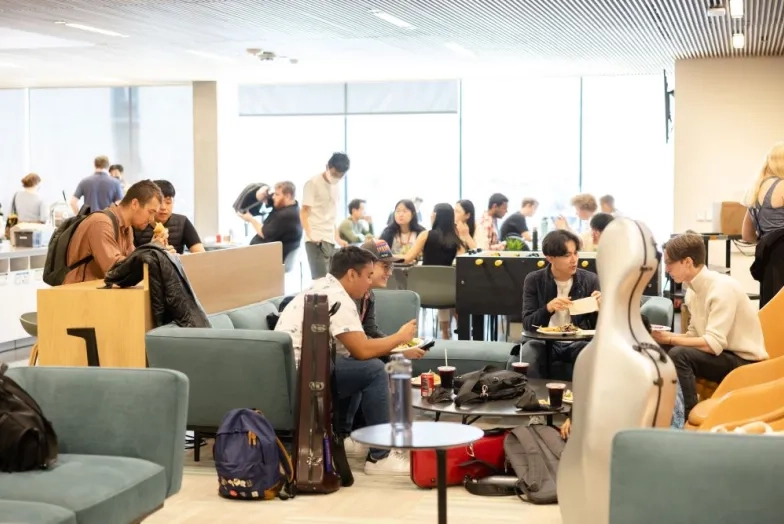 a lively lounge in the bowes center with students eating and talking