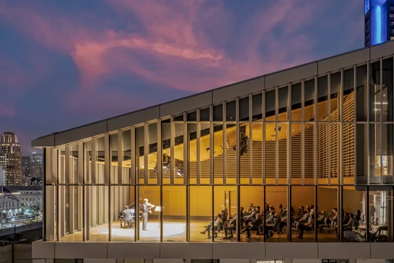 a drone photo of the top floor Osher recital hall during a recital. there is a sunset in teh background