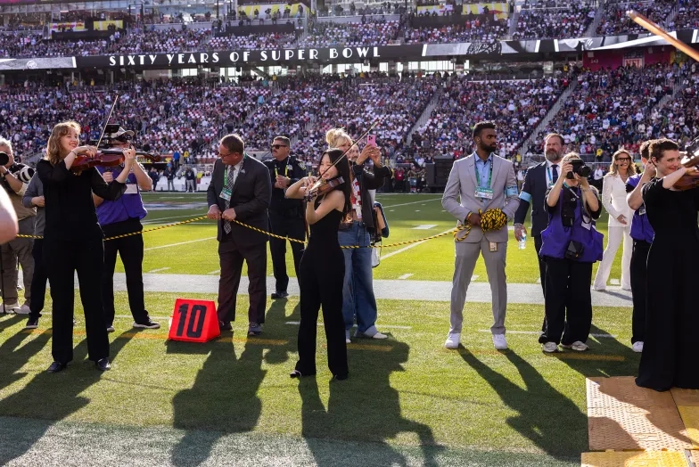 SFCM students play in a line as football stars enter the field.