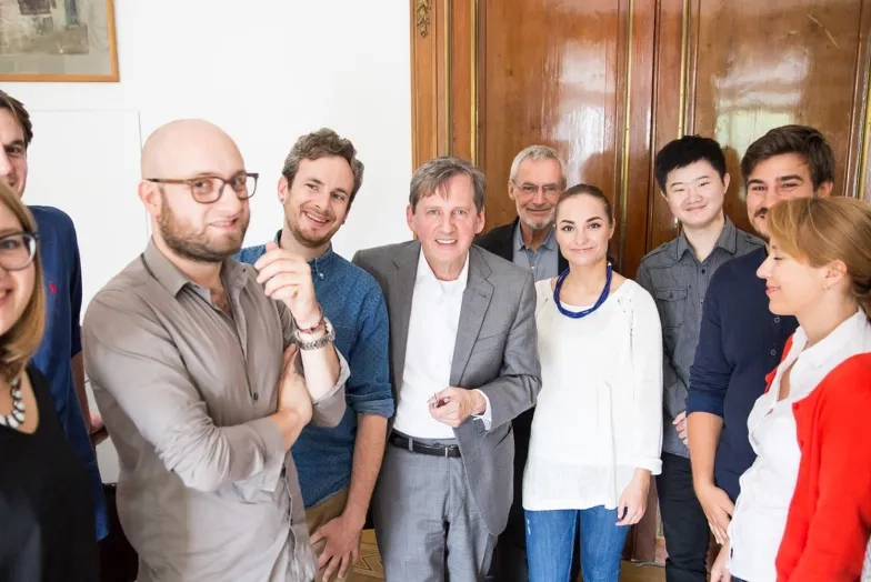 students and professor take a group photo in Hamburg sunny indoor hallway in front of wooden door
